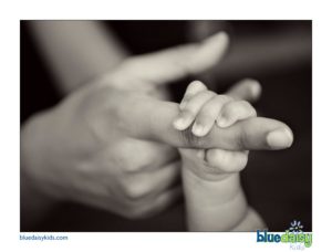 black and white photo of newborn baby holding mother's hand