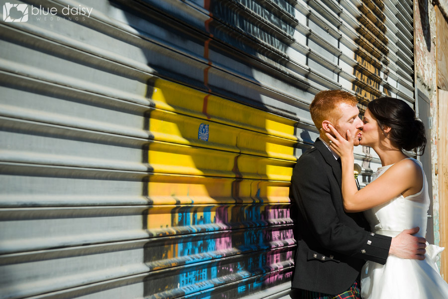 newlyweds kissing in front of graffiti