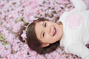 toddler girl laughing on cherry blossom petals